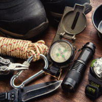 Outdoor travel equipment planning for a mountain trekking camping trip on wooden background. Top view - vintage film grain filter effect styles